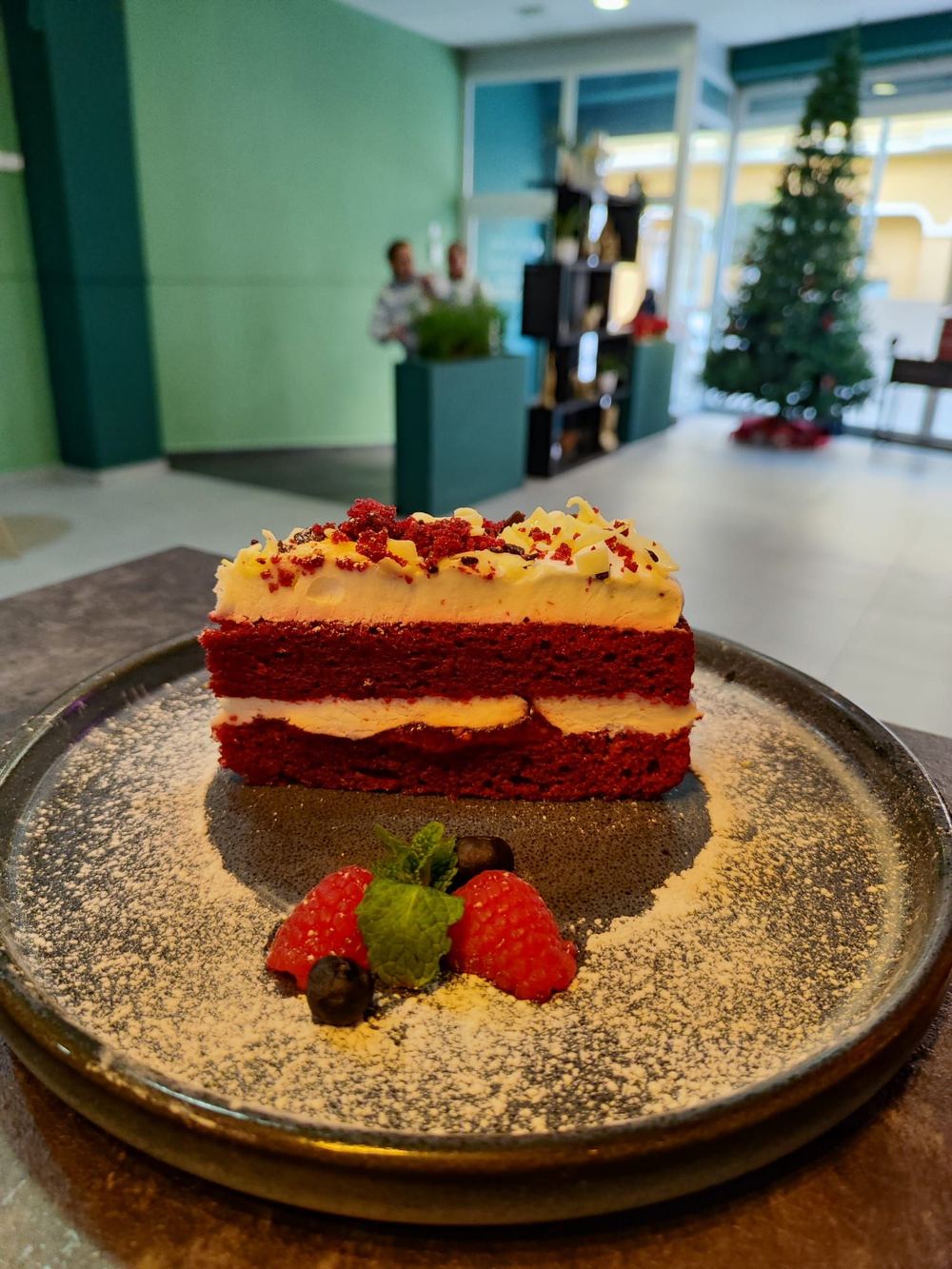Porción de tarta roja con crema y frutos rojos